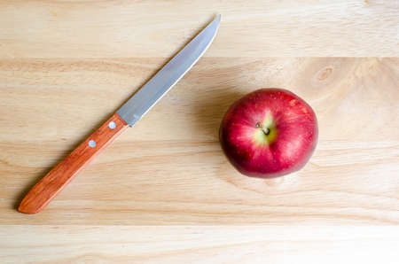 Red apple and knife on wooden tableの写真素材