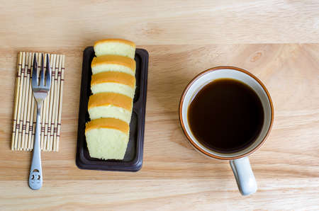 Coffee and slice of butter cake on wooden tableの写真素材