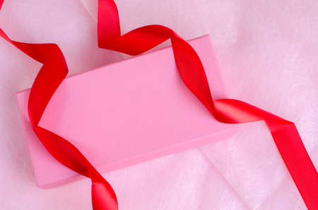 Pink gift box with ribbon on pink backgroundの写真素材