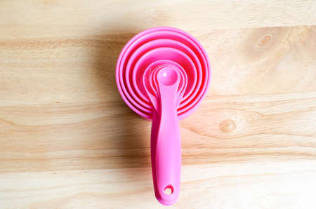 Pink measuring spoons in different sizes on wooden tableの写真素材