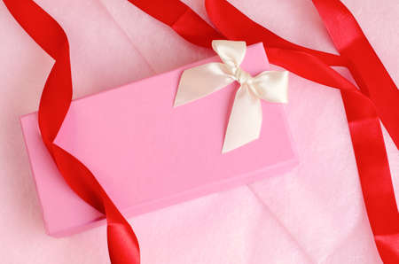 Pink gift box with ribbon on pink backgroundの写真素材