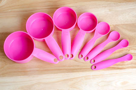 Pink measuring spoons in different sizes on wooden tableの写真素材