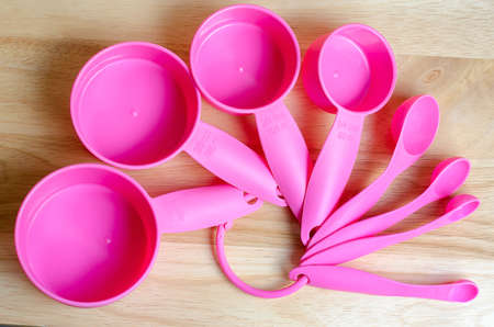 Pink measuring spoons in different sizes on wooden tableの写真素材