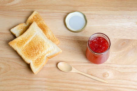Strawberry jam and toasted on wooden tableの写真素材
