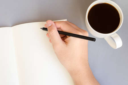 Hand write on the notebook with cup of coffee on tableの写真素材