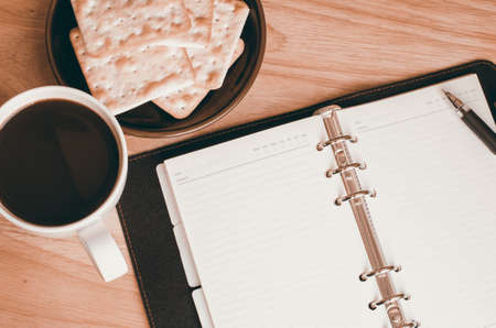 Blank open notebook with cup of coffee and biscuit on wooden table  vintage toneの写真素材