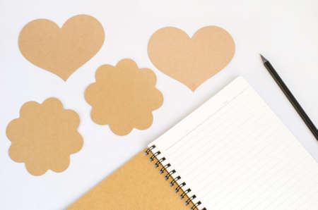Notebook from recycle paper and black pencil with group of different brown tag on white background - heart and flower tagの写真素材