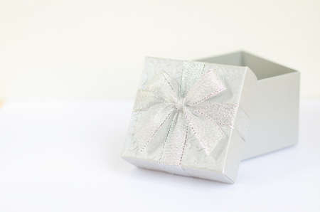 Gray gift box with bow ribbon opened on white backgroundの写真素材