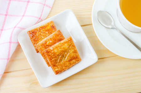 Homemade strawberry pie in white dish on wooden table with tea and napkin