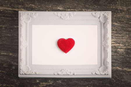 White retro frame with red heart on old wooden table with vintage and vignette tone - Valentine's day and love conceptの写真素材