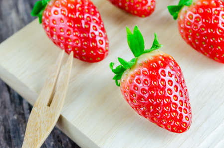 Red Strawberries wooden board with brown forkの写真素材