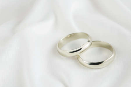Wedding rings on white satin textile backgroundの写真素材