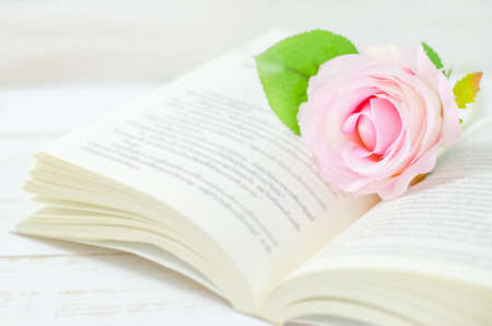 Pastel artificial rose and open book on white wooden table with soft vintage toneの写真素材