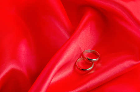 Wedding rings on red satin textile backgroundの写真素材