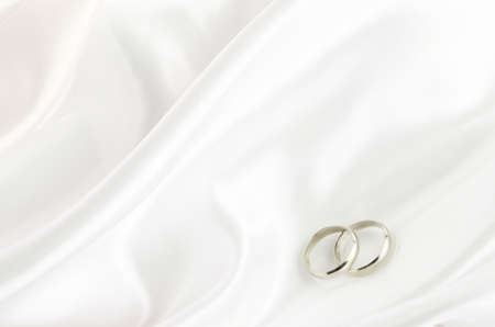 Wedding rings on white satin textile backgroundの写真素材