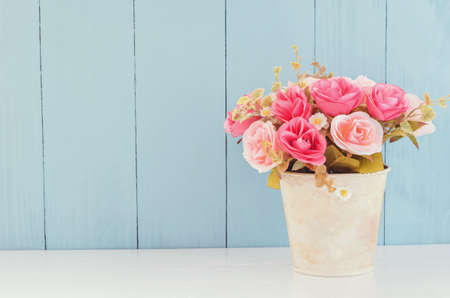 Pastel Artificial Pink Rose Wedding Bridal Bouquet in flower pot on white and blue wooden background with soft vintage toneの写真素材