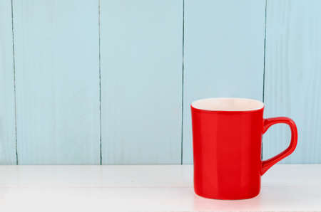 Red coffee mug with hot steam on white and blue backgroundの写真素材