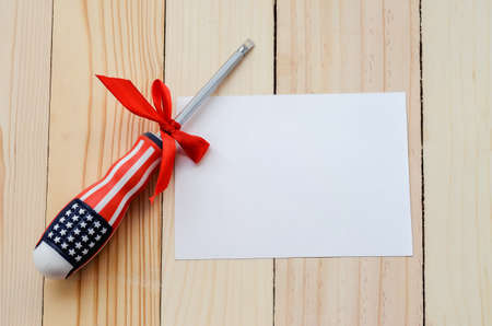 Screwdriver with flag of The United States of America pattern on wooden table with red ribbon bow and blank greeting card paper - Labor Dayの写真素材