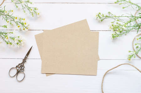 Blank greeting card with brown envelop and daisy flowers on white wooden table with vintage toneの写真素材