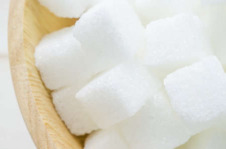 Close up of white cube refined sugars in brown wooden bowlの写真素材