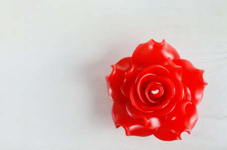 Red aromatherapy candle with rose shape on white wooden tableの写真素材