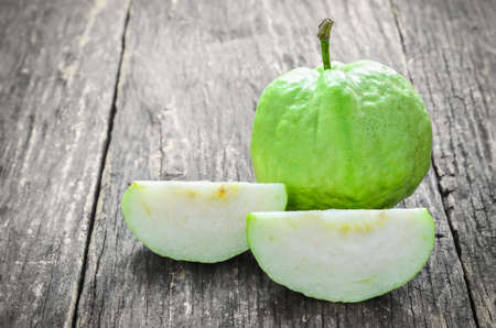 Slice of green Guava and fresh Guava on old wooden table with vignette toneの写真素材