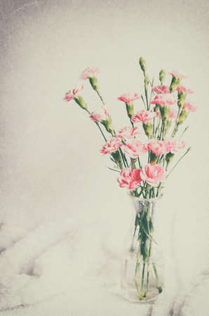 Pink Carnation flowers in glass bottle vase with vintage and vignette toneの写真素材