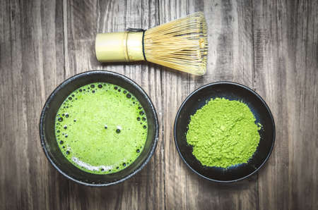 Japanese matcha green tea and matcha green tea powder at homemade clay bowl with bamboo whisk on...