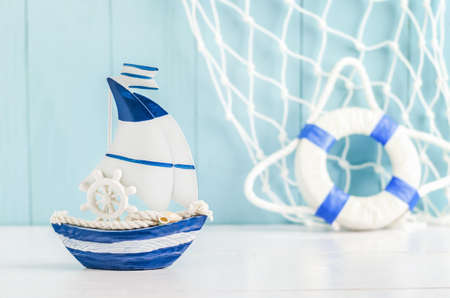 Sail boat Toy model with Ship'wheel, rope and seashell on white and blue wooden background - Nautical backgroundの写真素材