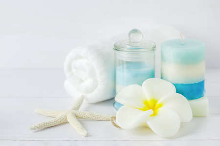 Spa soap with Plumeria flower shape and aromatherapy spa tools, towel, blue aroma spa salt, layered aroma spa candle, starfish on white wooden backgroundの写真素材