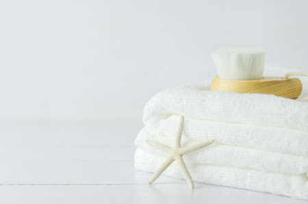 Close up of starfish and white towels with Facial cleansing brush on white wooden backgroundの写真素材