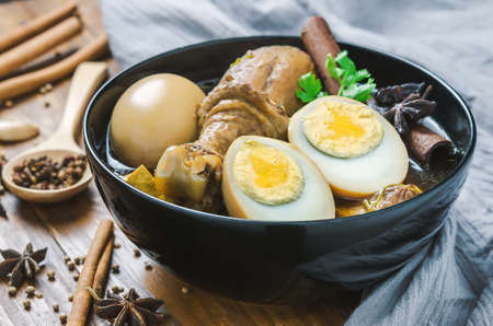 Eggs and chicken stew with spices and brown sauce in black bowl on wooden table, Asian food, Chinese food, Thailand foodの写真素材