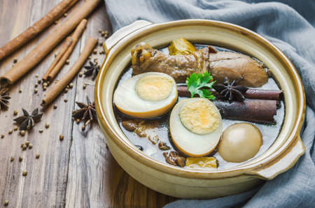 Eggs and chicken stew with spices and brown sauce in clay pot on wooden table, Asian food, Chinese food, Thailand foodの写真素材
