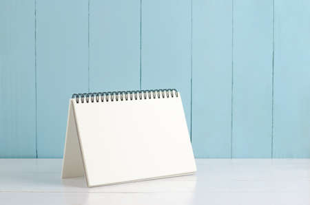 Blank desk calendar on white and blue wooden background, Blank notebook on wooden tableの写真素材