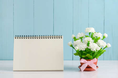 Blank desk calender card paper and beautiful Jasmine flower bouquet with pink ribbon bow on white and blue wooden background - Jasmine is the symbol of Mother's Day in Thailand.の写真素材
