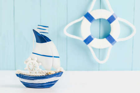Sail boat Toy model with Ship'wheel, rope and seashell on white and blue wooden background -...