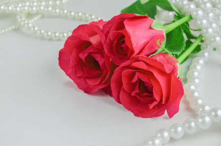 Close up of red rose flowers with white pearls necklace on white backgroundの写真素材