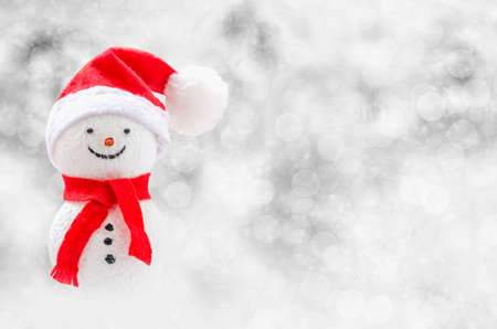 Christmas background - Cute Snowman with red scarf and red santa claus hat on sparkle white bokeh light backgroundの写真素材