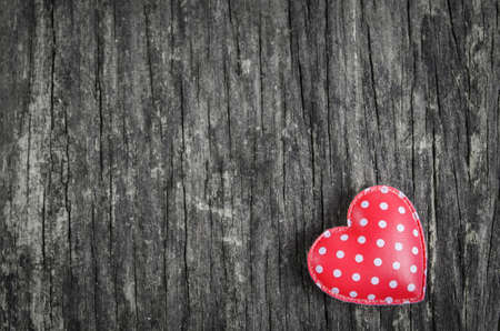 Red retro heart with white polka dot pattern on old wooden table with vintage and vignette toneの写真素材
