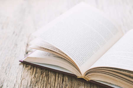 Old book opened on dirty wooden background with vintage toneの写真素材
