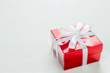 Close up of red gift box with white ribbon bow on white backgroundの写真素材