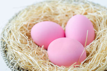 Close up of pink pastel easter eggs at wooden wool and wooden basket on white background, Easter backgroundの写真素材