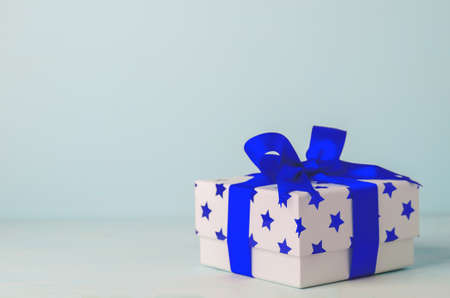 White gift box with blue star pattern and blue ribbon bow on blue wooden background - Christmas backgroundの写真素材