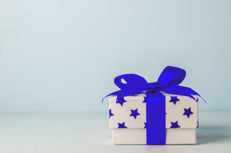 White gift box with blue star pattern and blue ribbon bow on blue wooden background - Christmas backgroundの写真素材