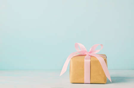 Brown gift box with pink ribbon bow on blue wooden background with soft vintage toneの写真素材