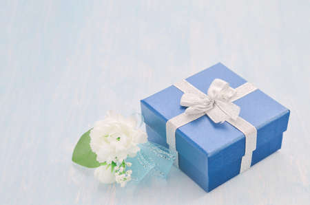Close up of blue gift box with silver ribbon bow and Jasmine flower bouquet with blue ribbon bow on white and blue wooden background - Jasmine is the symbol of Mother's Day in Thailand.の写真素材