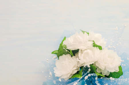 Close up of artificial Jasmine flower bouquet with blue ribbon bow on white and blue wooden background - Jasmine is the symbol of Mother's Day in Thailand.の写真素材