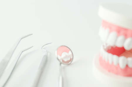 Close up of dental mirror with teeth model and dental equipment on white backgroundの写真素材