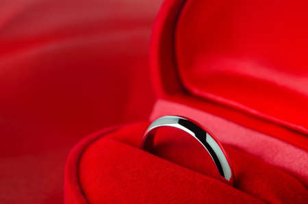 Close up of wedding ring at red velvet jewelry box on red satin backgroundの写真素材