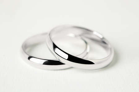 Close up of couple wedding rings on white wooden backgroundの写真素材